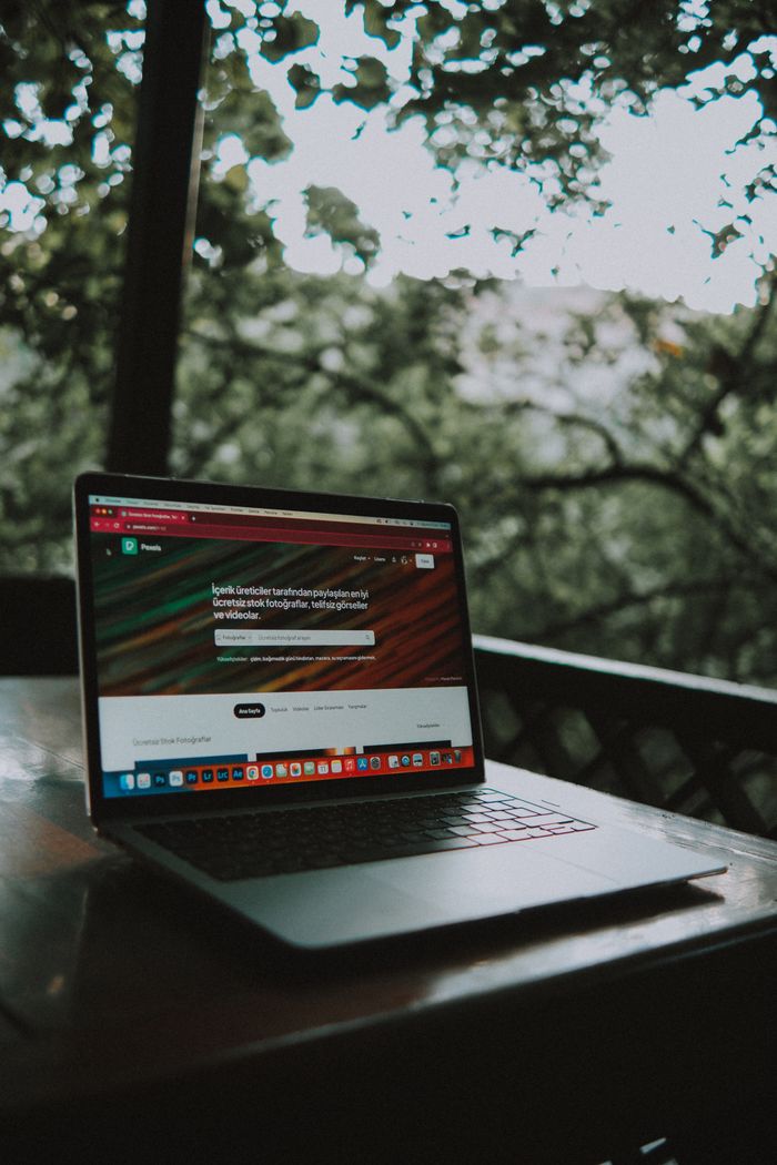creative-01 Open laptop showing a website screen on a wooden table in an outdoor terrace setting.